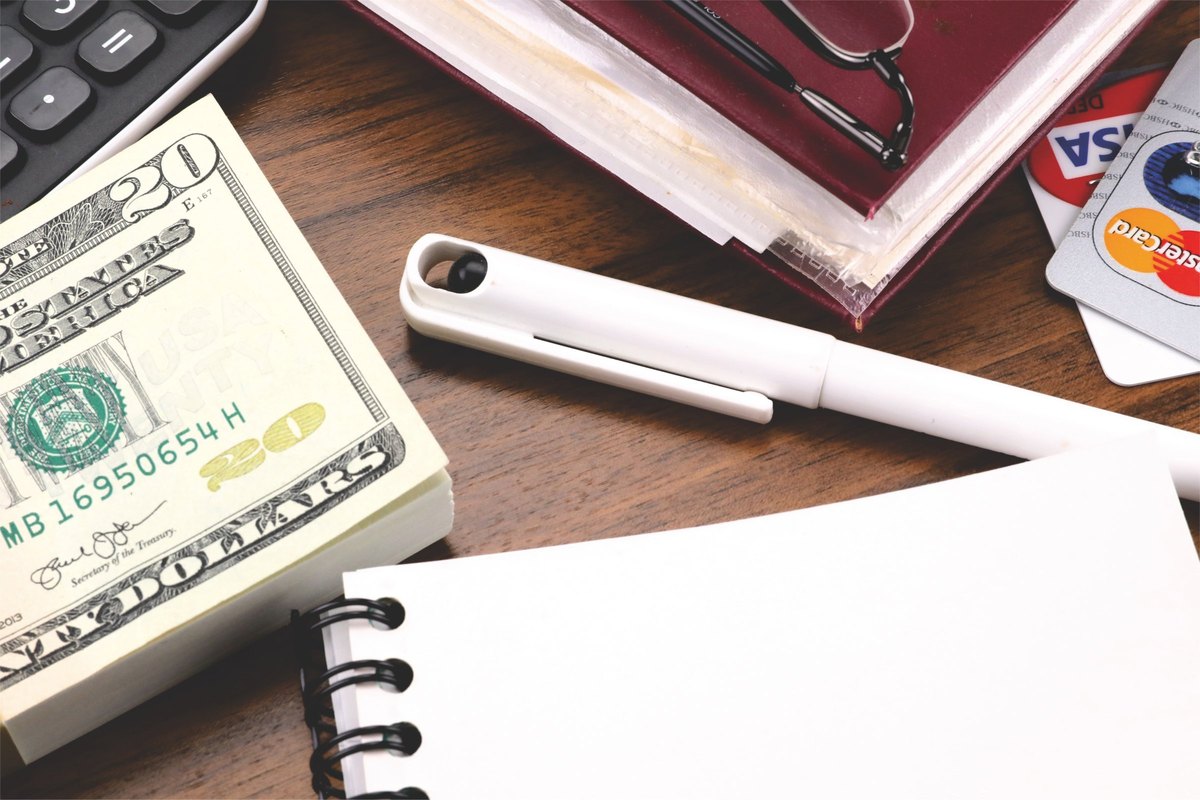 Spiral notepad with a blank page, pen and dollar bills - blank template