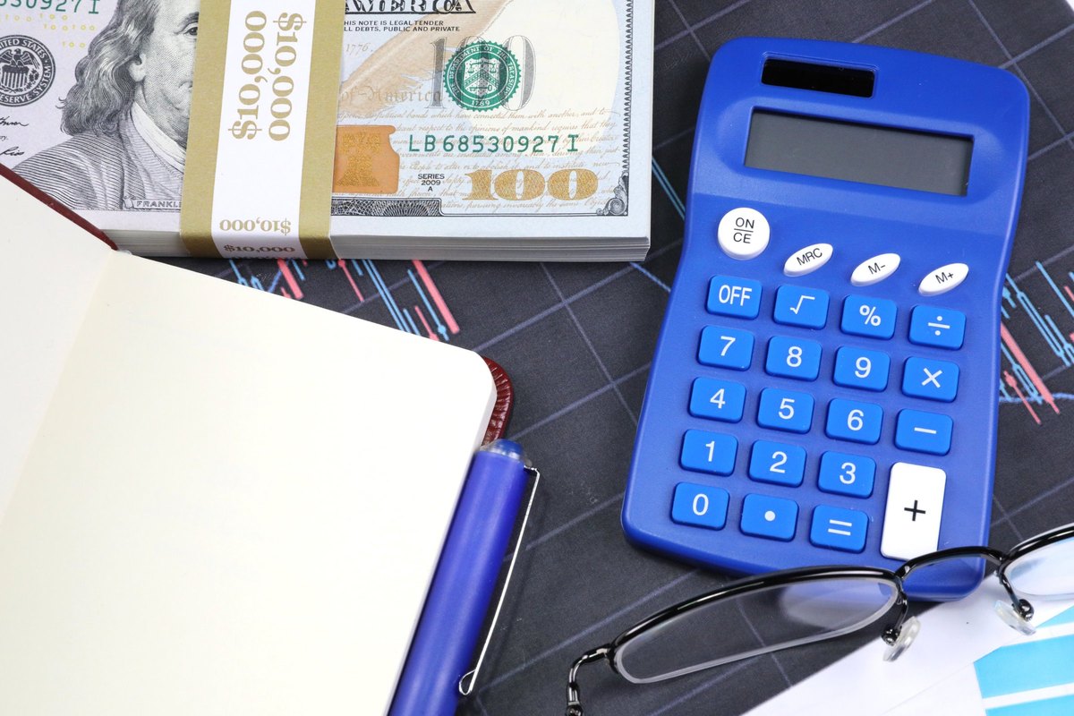 Open notebook with dollars and blue calculator - blank template