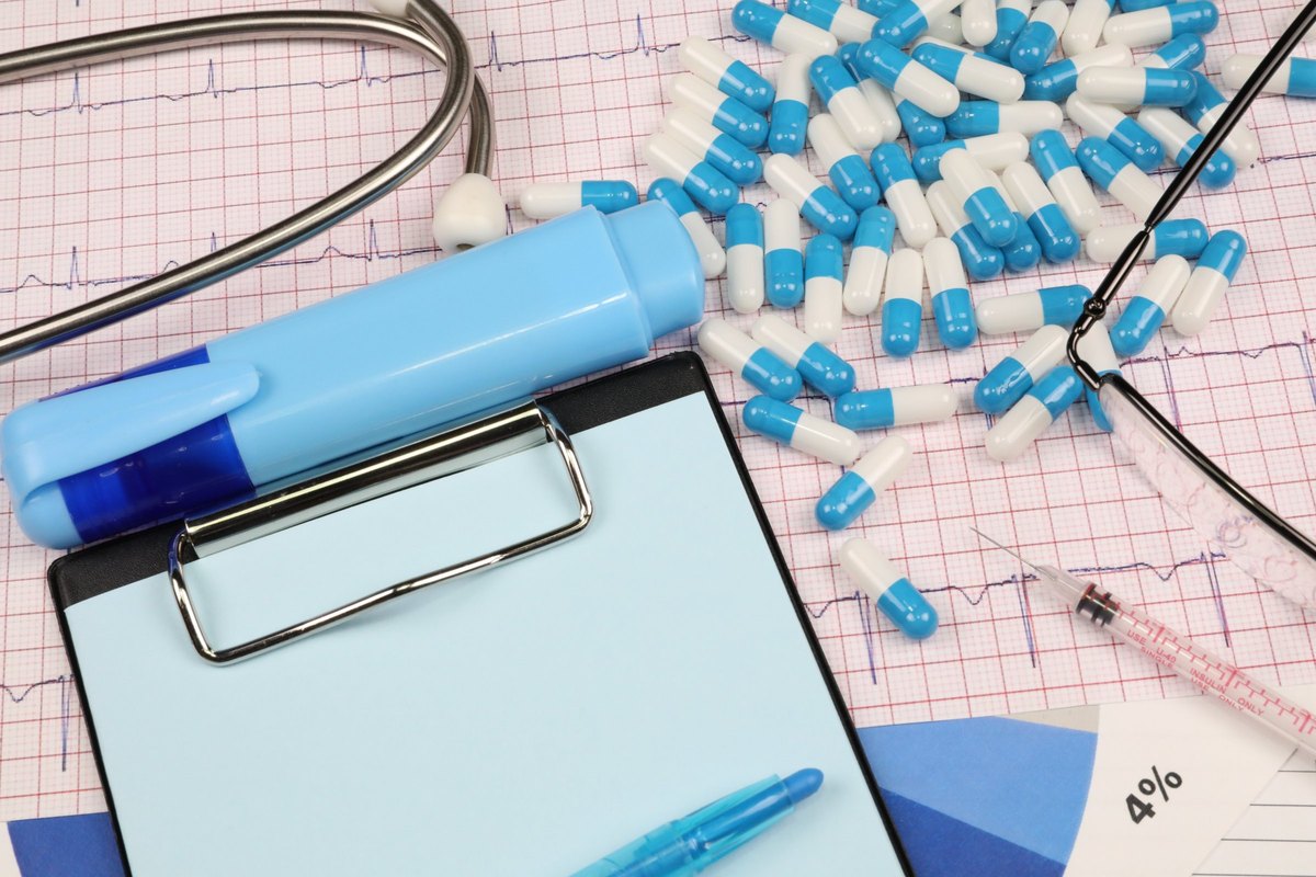 Clipboard with pale blue paper, capsules and glasses - blank template