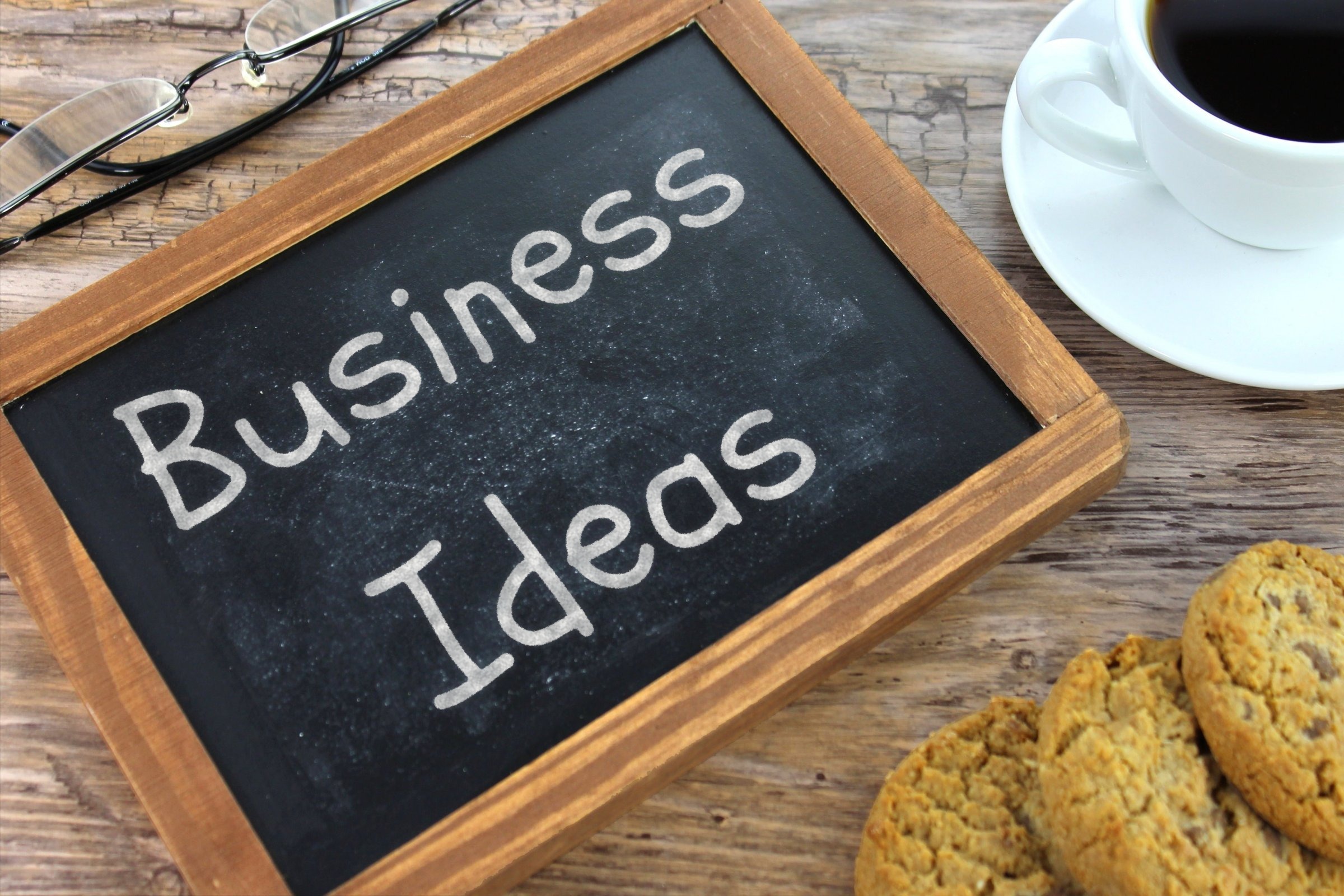 Chalkboard slate with glasses, coffee and cookies template with the words "Business Ideas" written in chalk