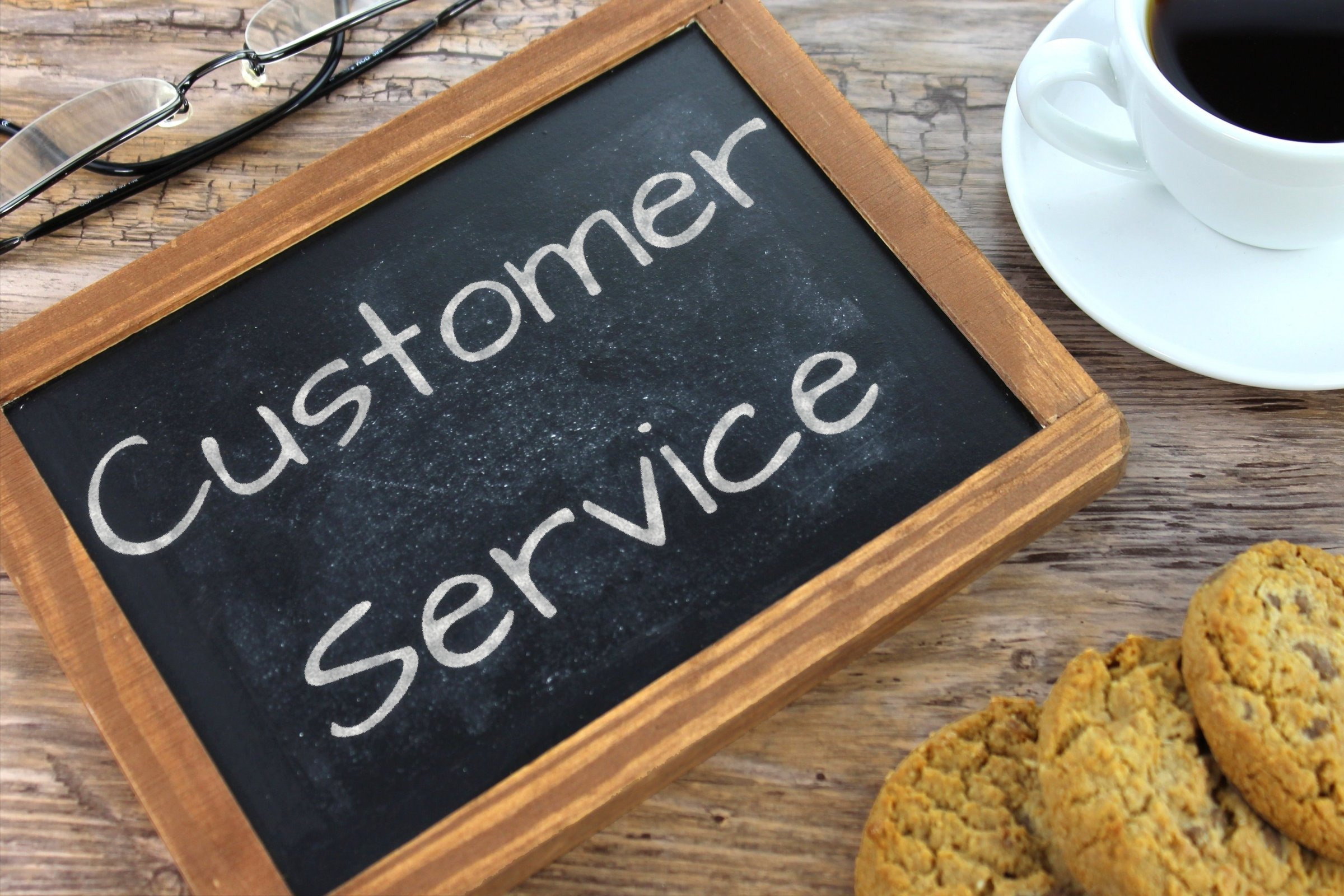 Chalkboard slate with glasses, coffee and cookies template with the words "Customer Service" written in chalk