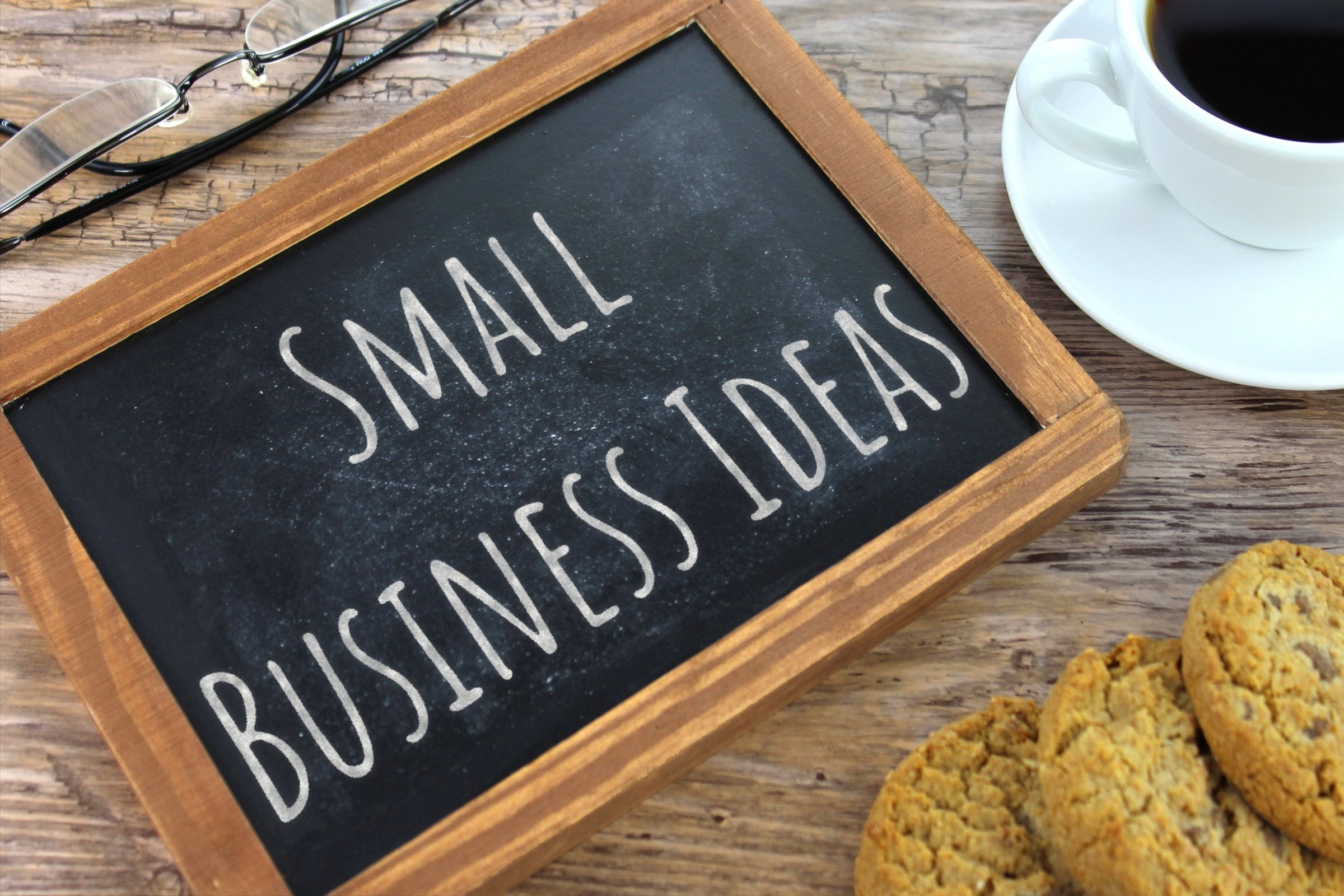 Chalkboard slate with glasses, coffee and cookies template with the words "Small Business Ideas" written in chalk