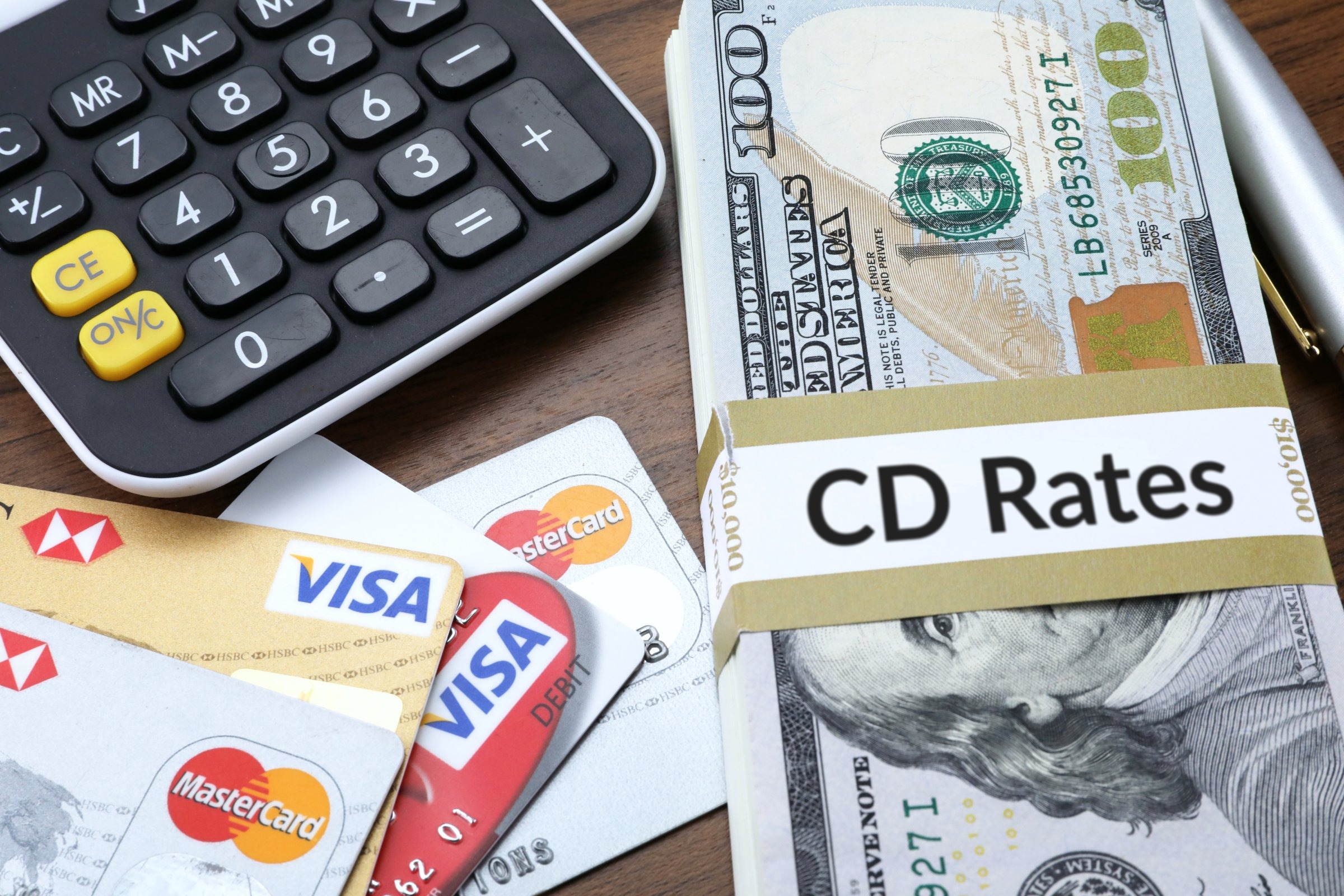 Banded stack of dollar bills with calculator and bank cards template with the words "CD Rates" printed on the surface