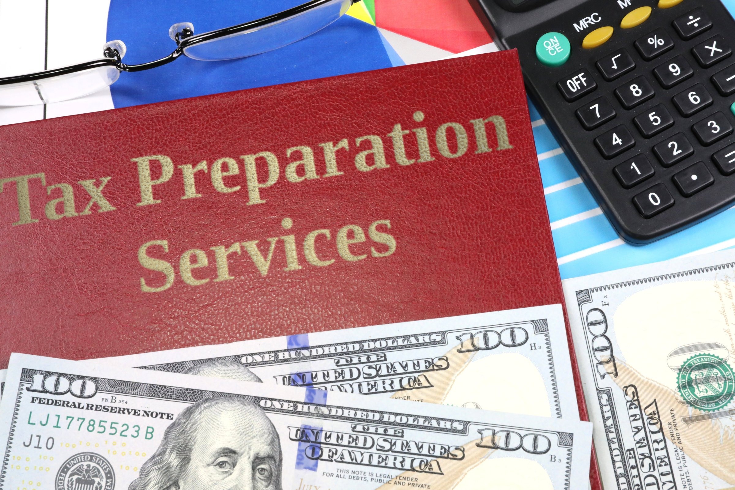 Red leather-look book with dollars and calculator template with the words "Tax Preparation Services" in metallic foil lettering