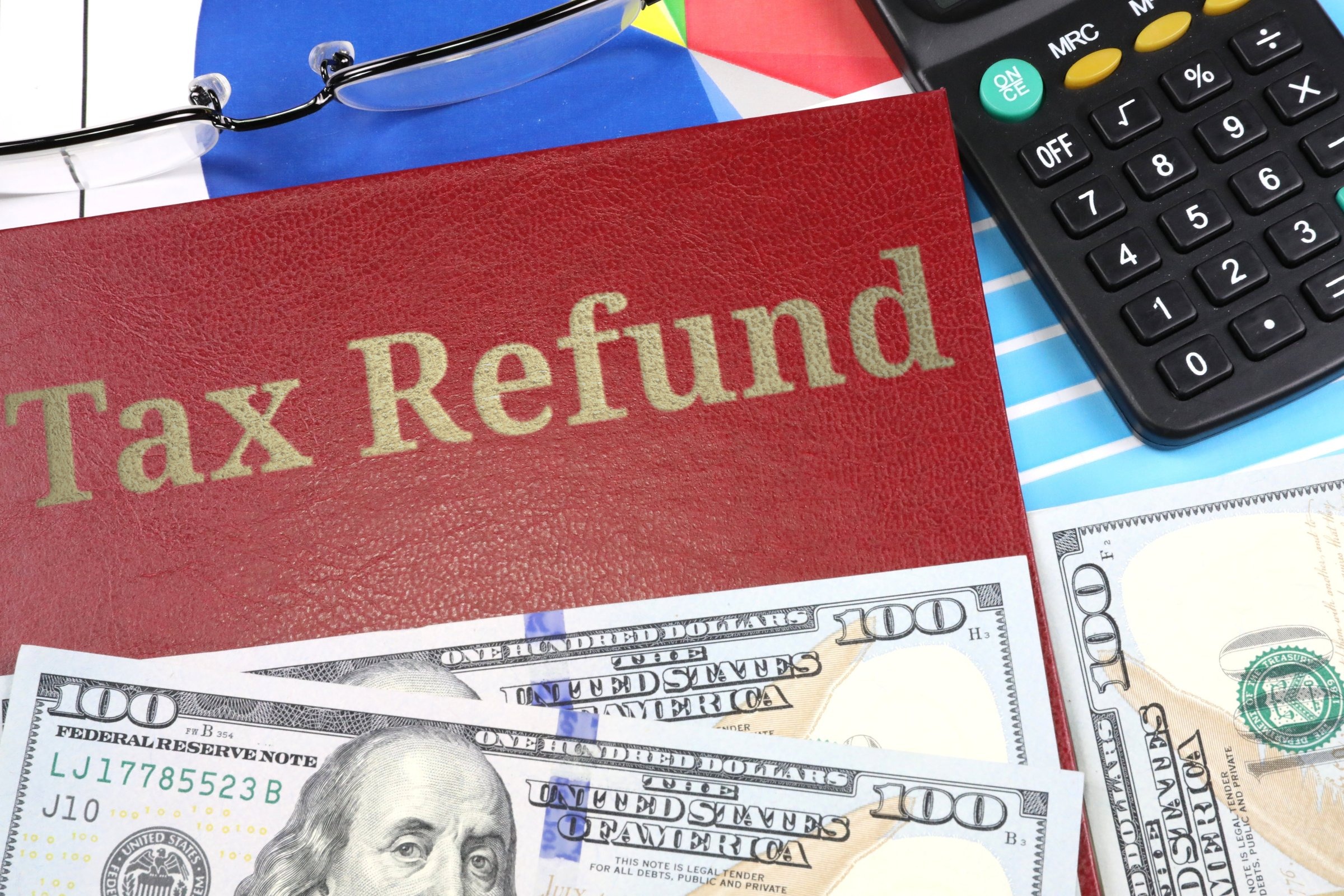 Red leather-look book with dollars and calculator template with the words "Tax Refund" in metallic foil lettering