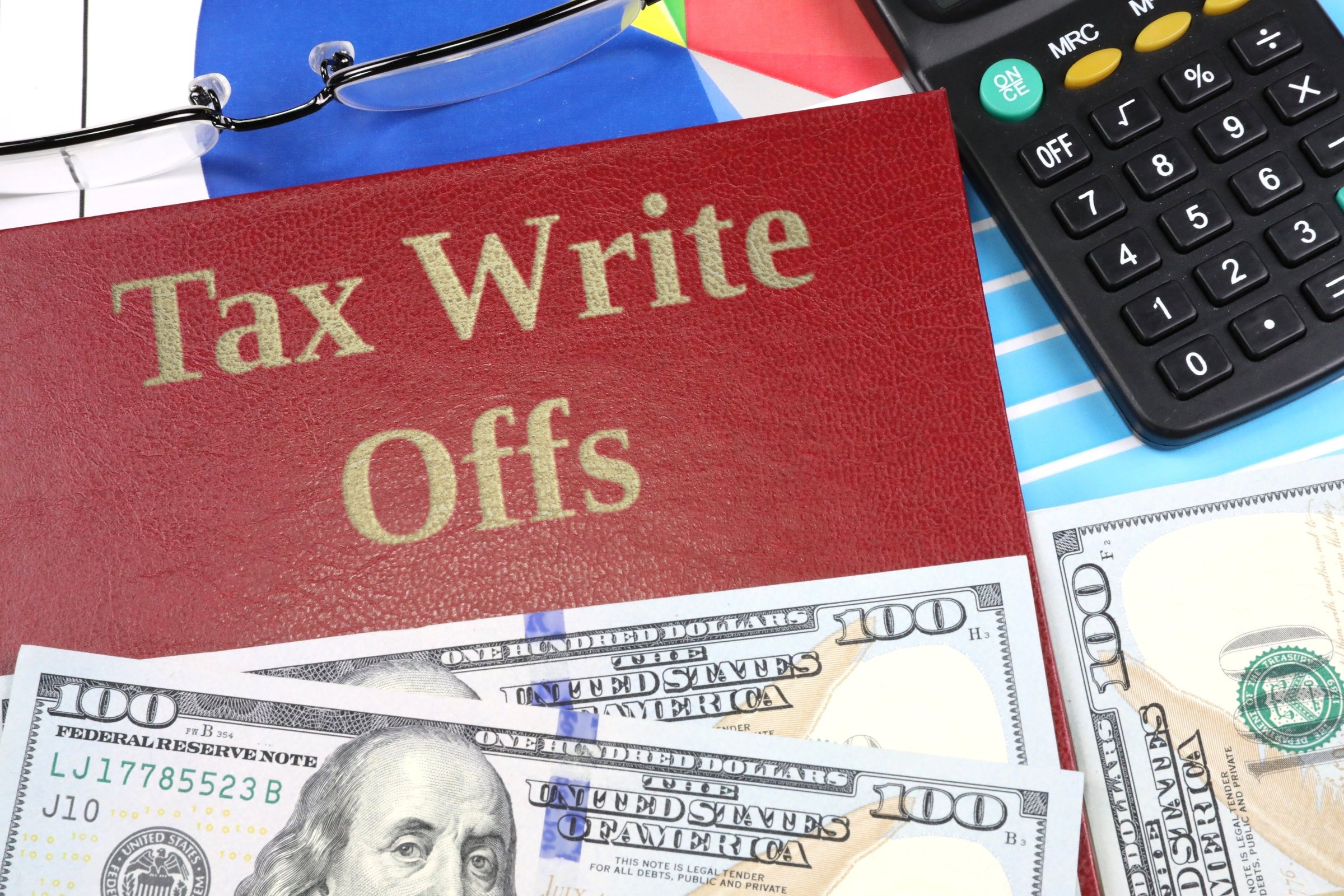 Red leather-look book with dollars and calculator template with the words "Tax Write Offs" in metallic foil lettering
