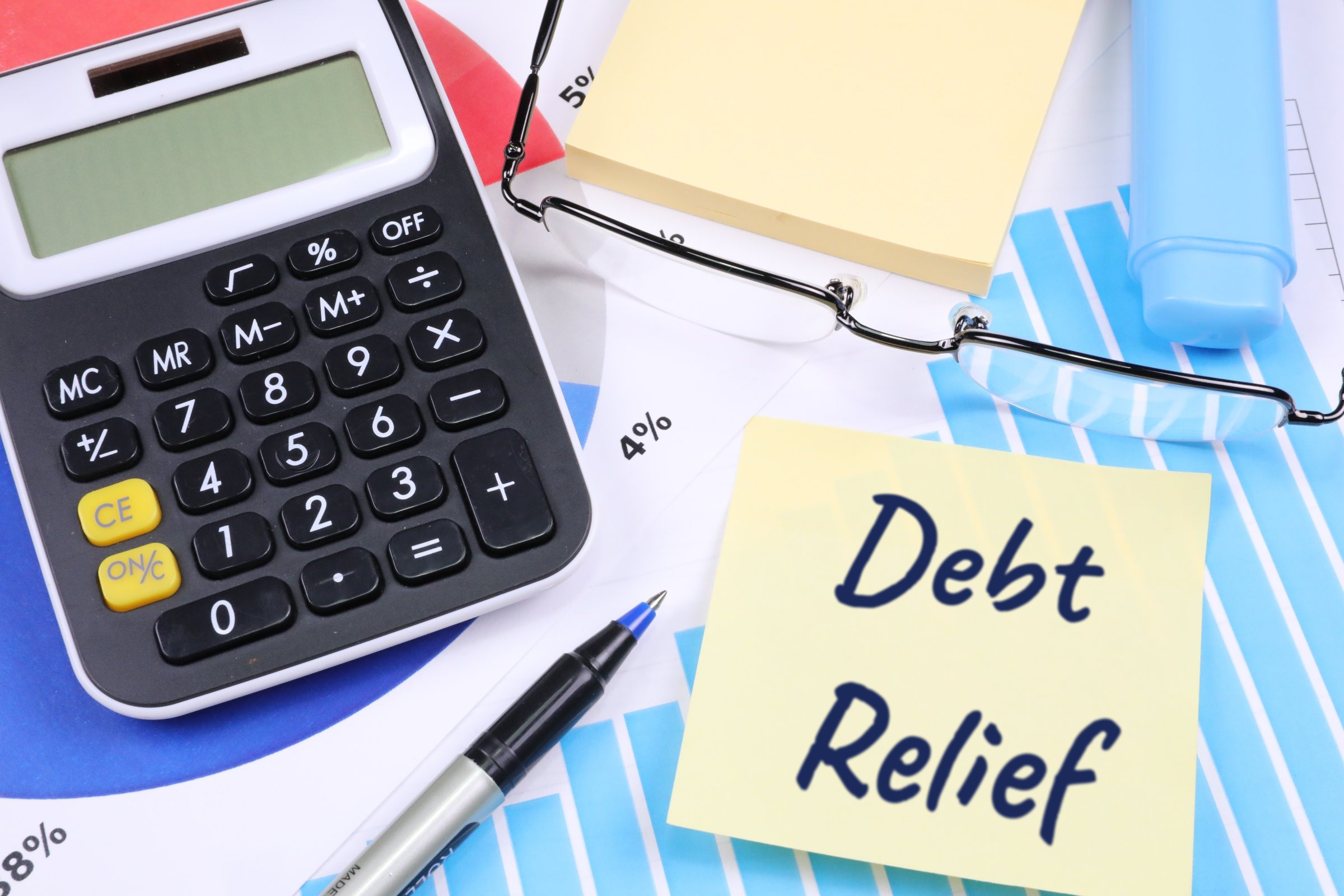 Sticky notes with calculator, glasses and pen template with the words "Debt Relief" printed on the surface