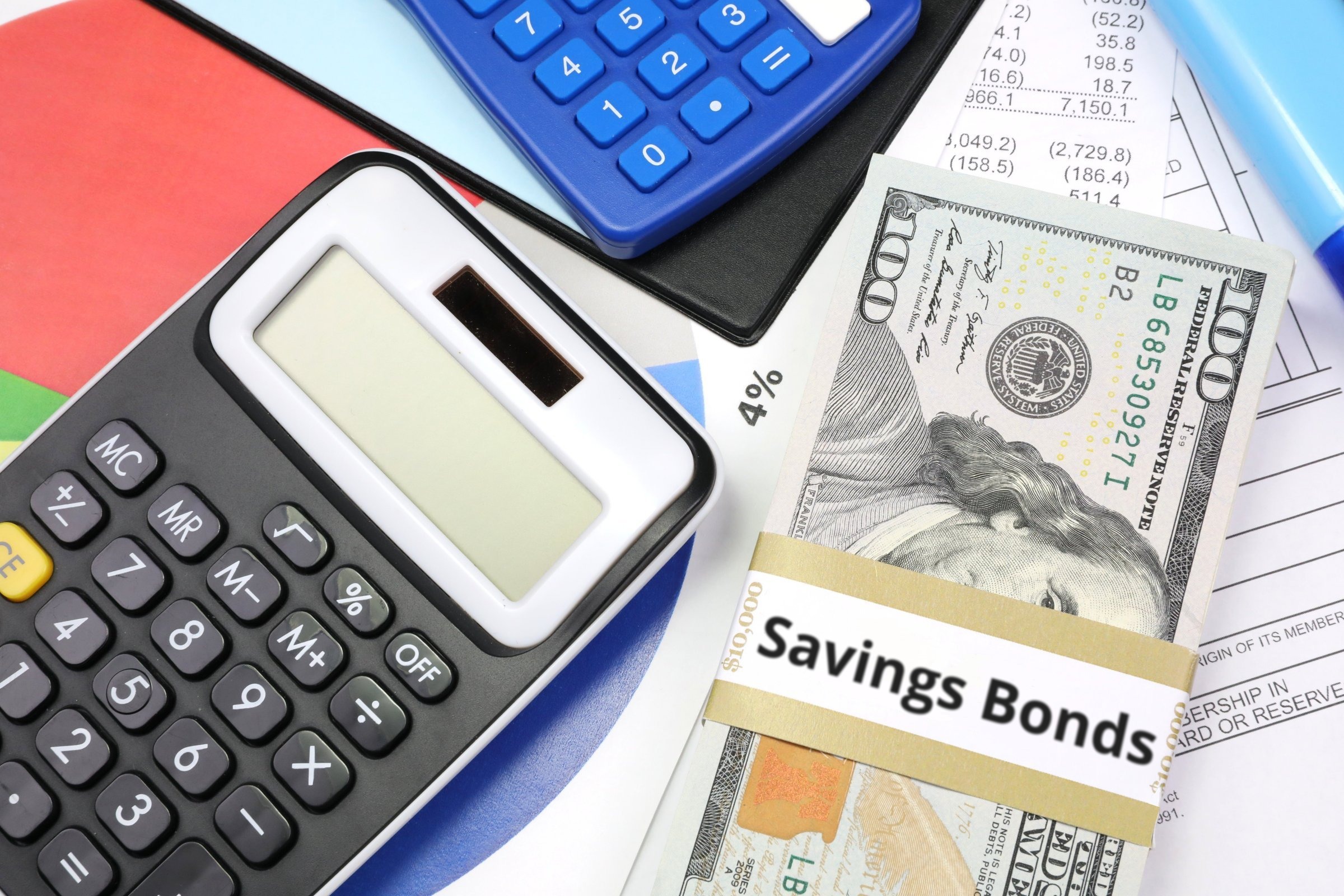 Dollar bills with a blank band, calculators and charts template with the words "Savings Bonds" printed on the surface