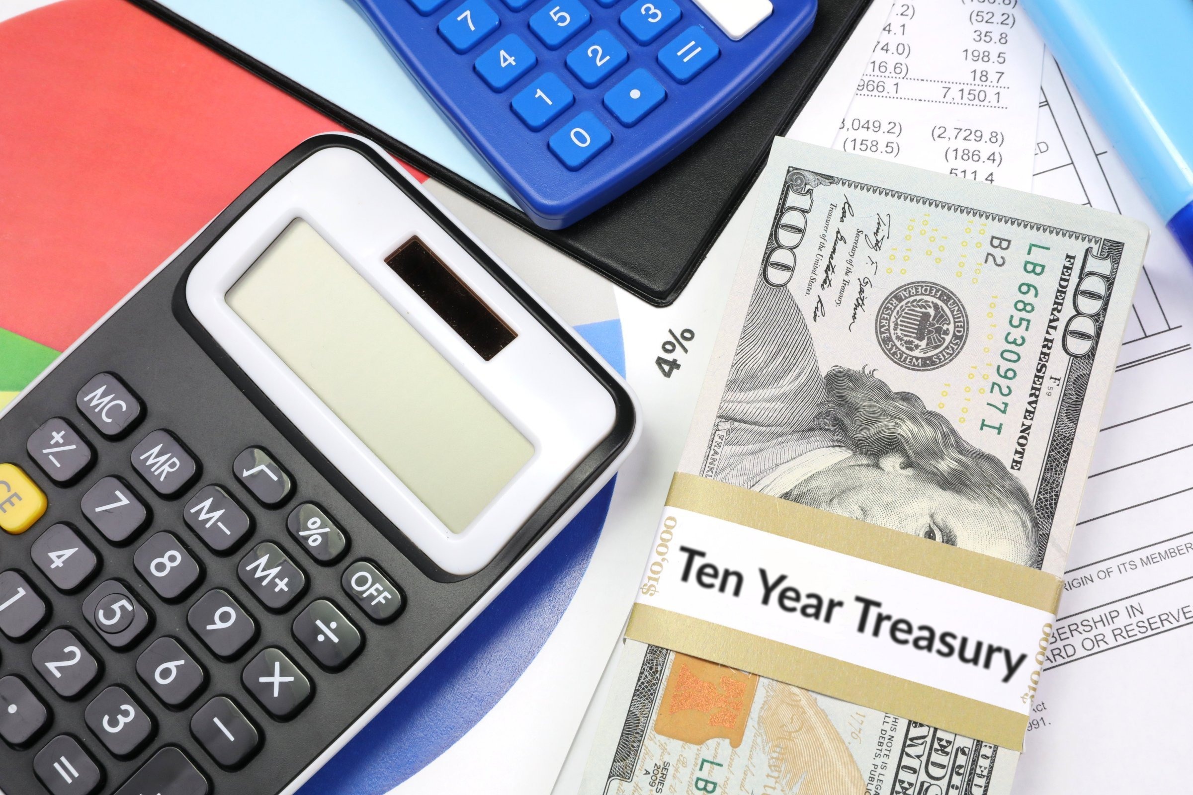 Dollar bills with a blank band, calculators and charts template with the words "Ten Year Treasury" printed on the surface
