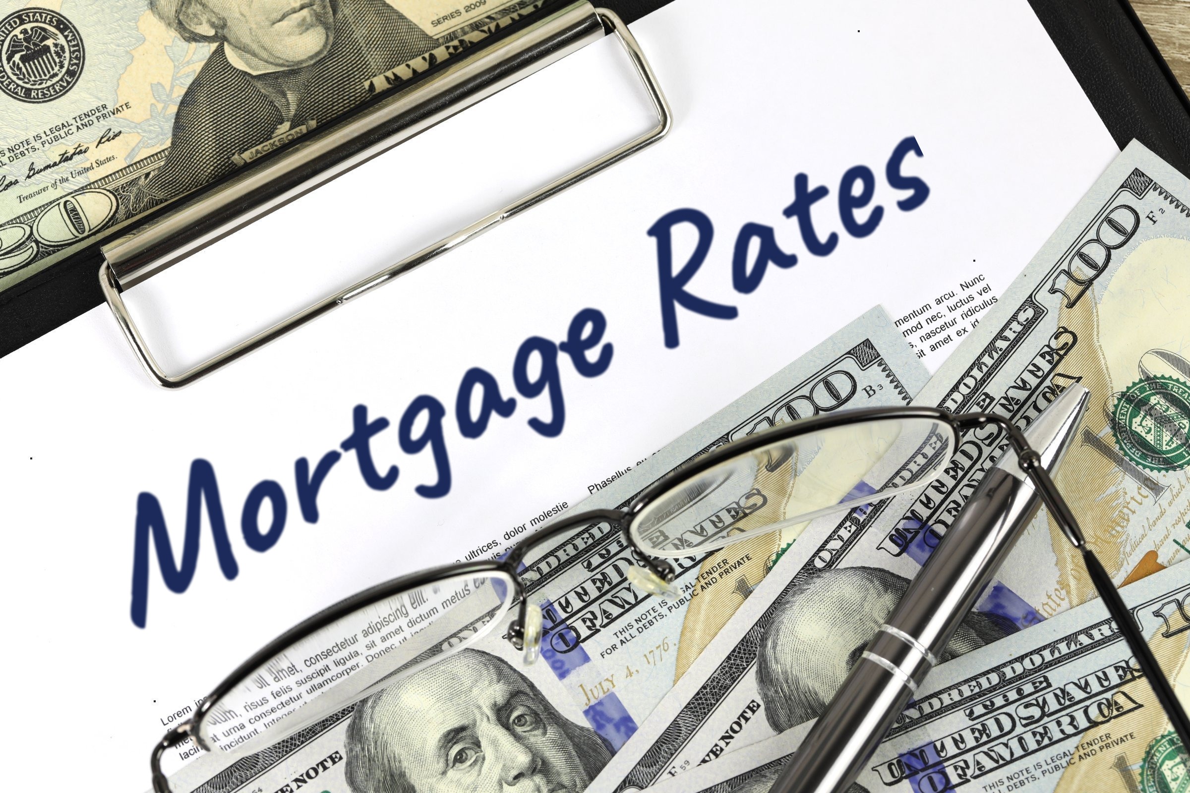 Blank paper on a clipboard with dollar bills and glasses template with the words "Mortgage Rates" printed on the surface