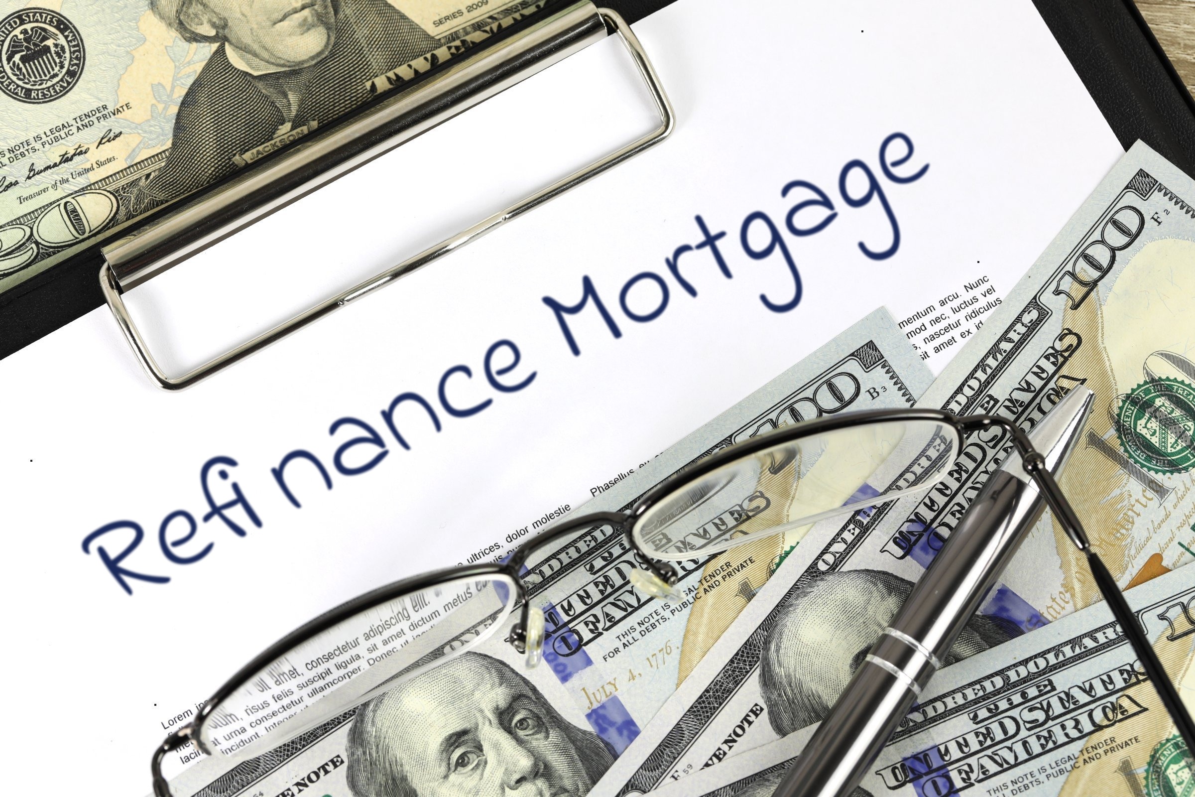 Blank paper on a clipboard with dollar bills and glasses template with the words "Refinance Mortgage" printed on the surface