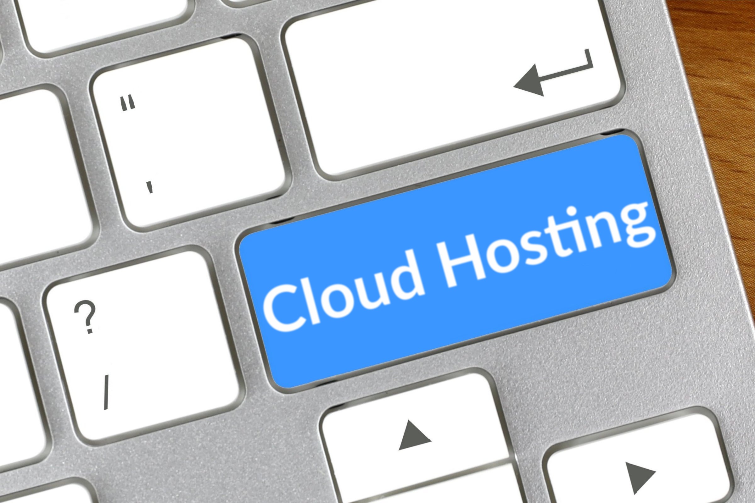 Computer keyboard with a blank blue key template with the words "Cloud Hosting" printed on the surface