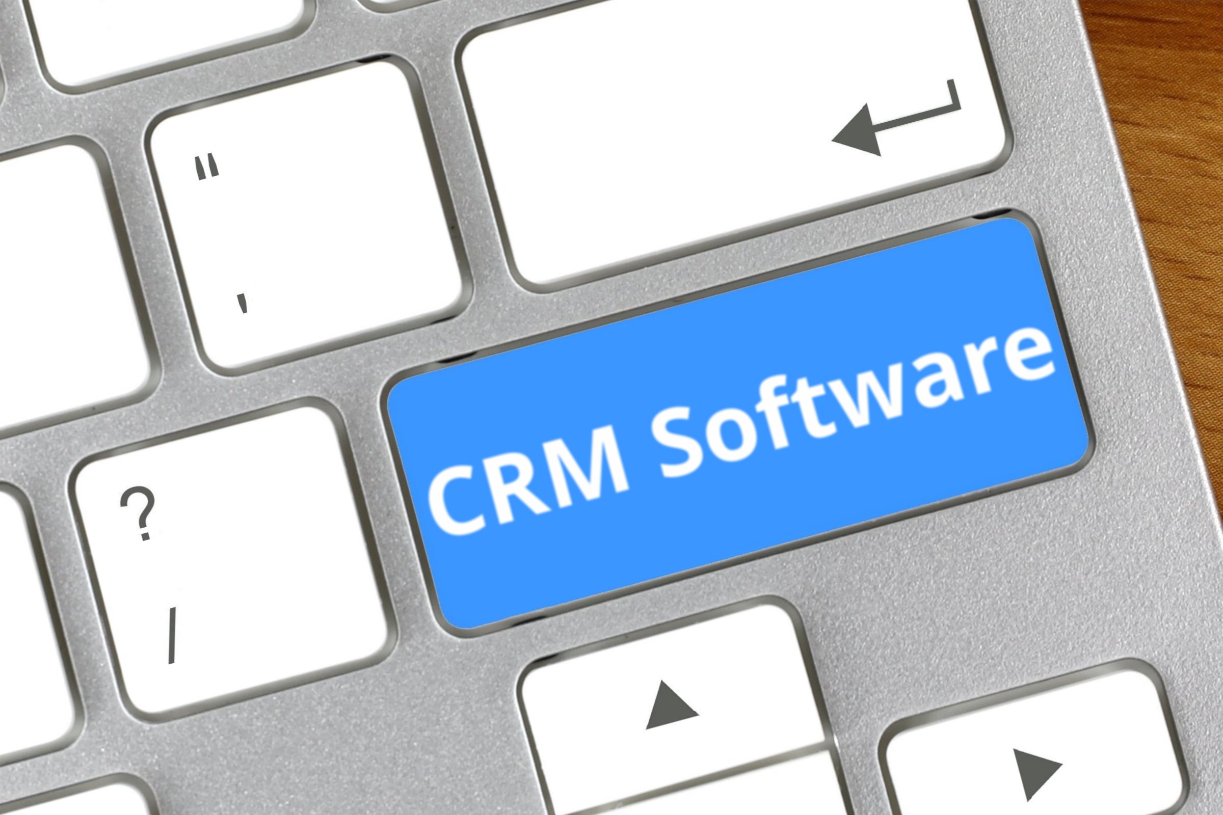 Computer keyboard with a blank blue key template with the words "CRM Software" printed on the surface