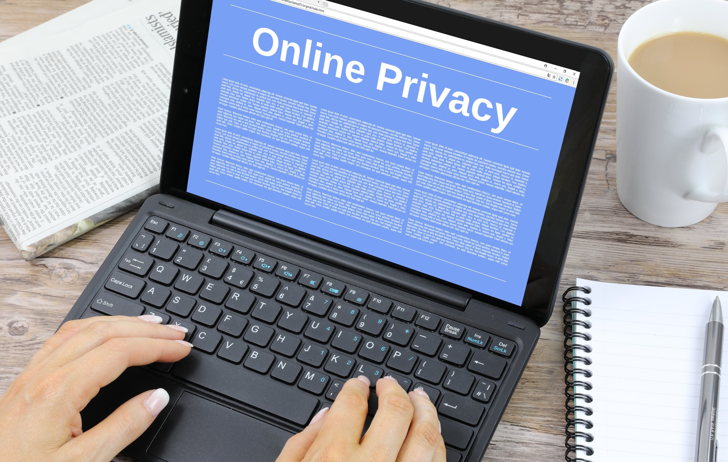 Laptop with a blank blue screen, tea and notepad template with the words "Online Privacy" in plain lettering