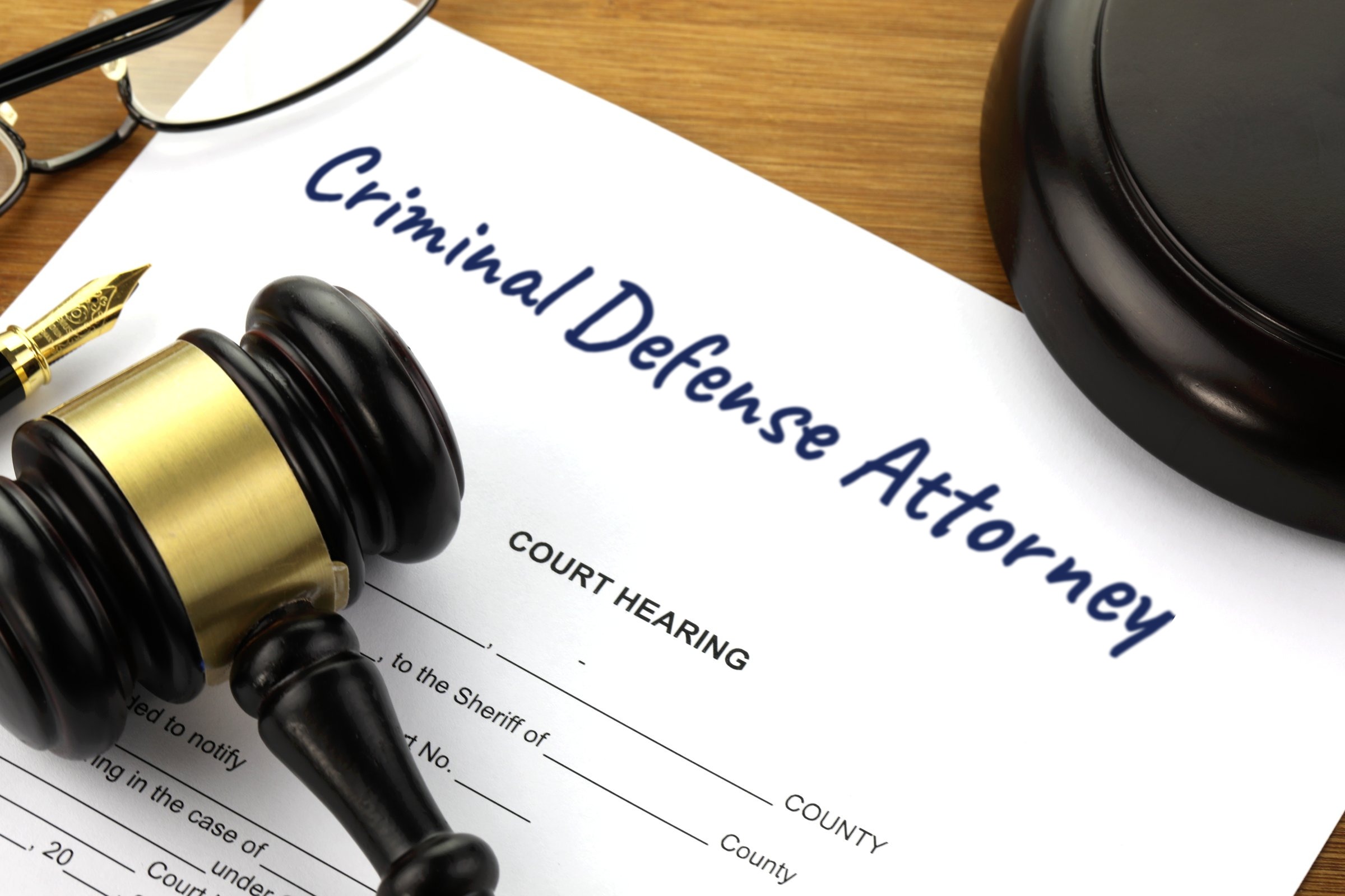 Court hearing document with gavel and fountain pen template with the words "Criminal Defense Attorney" printed on the surface