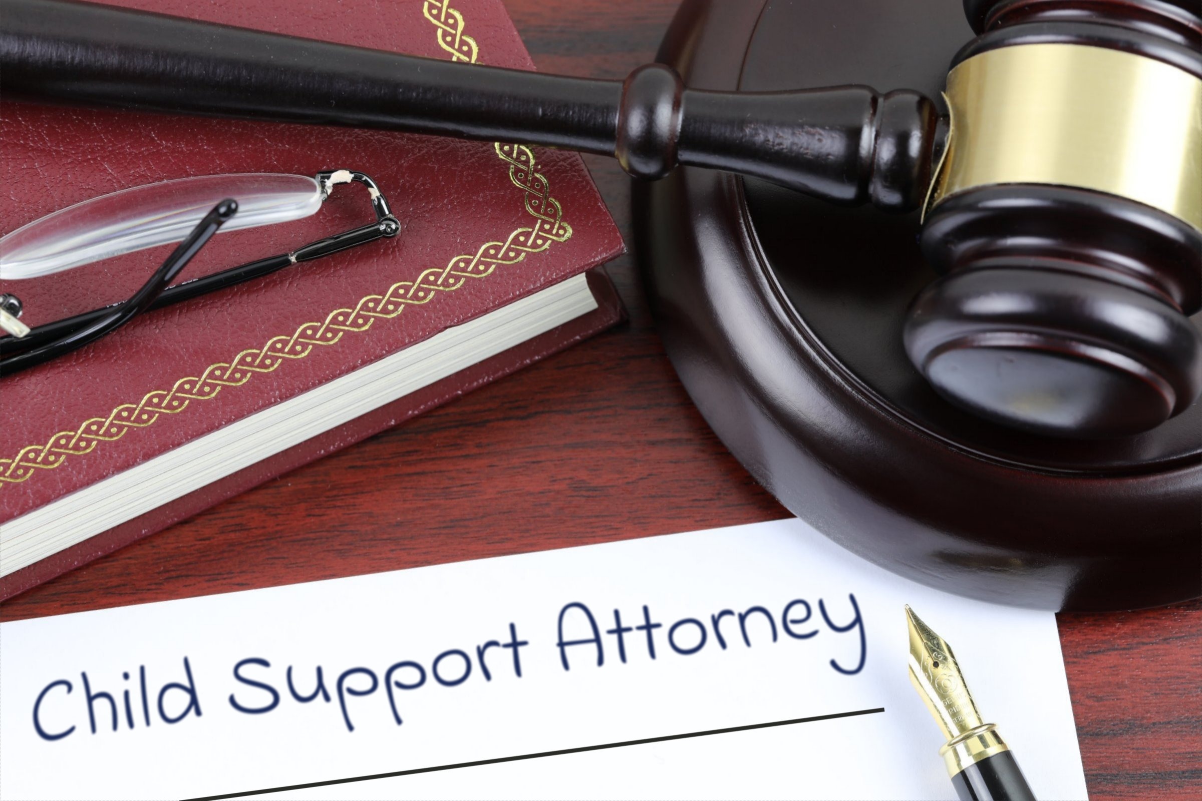 Blank paper with red book, gavel and fountain pen template with the words "Child Support Attorney" printed on the surface
