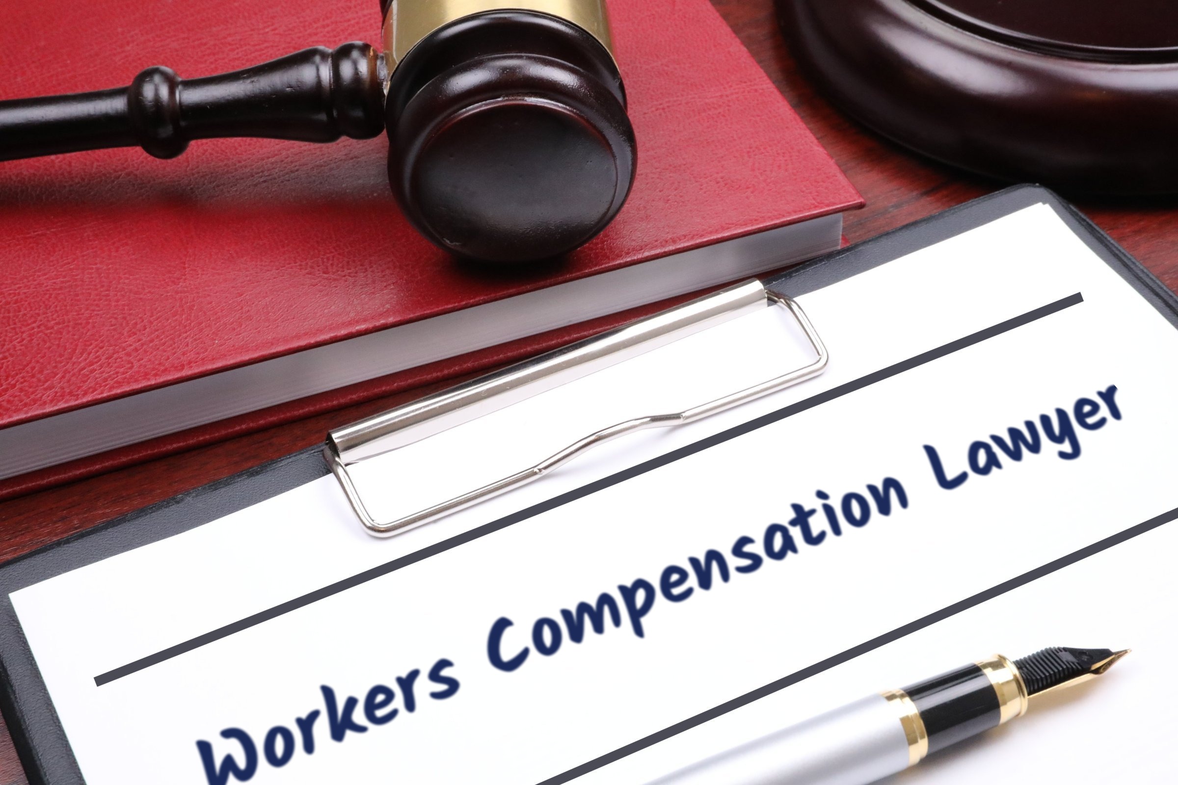 Clipboard with red book, gavel and fountain pen template with the words "Workers Compensation Lawyer" printed on the surface