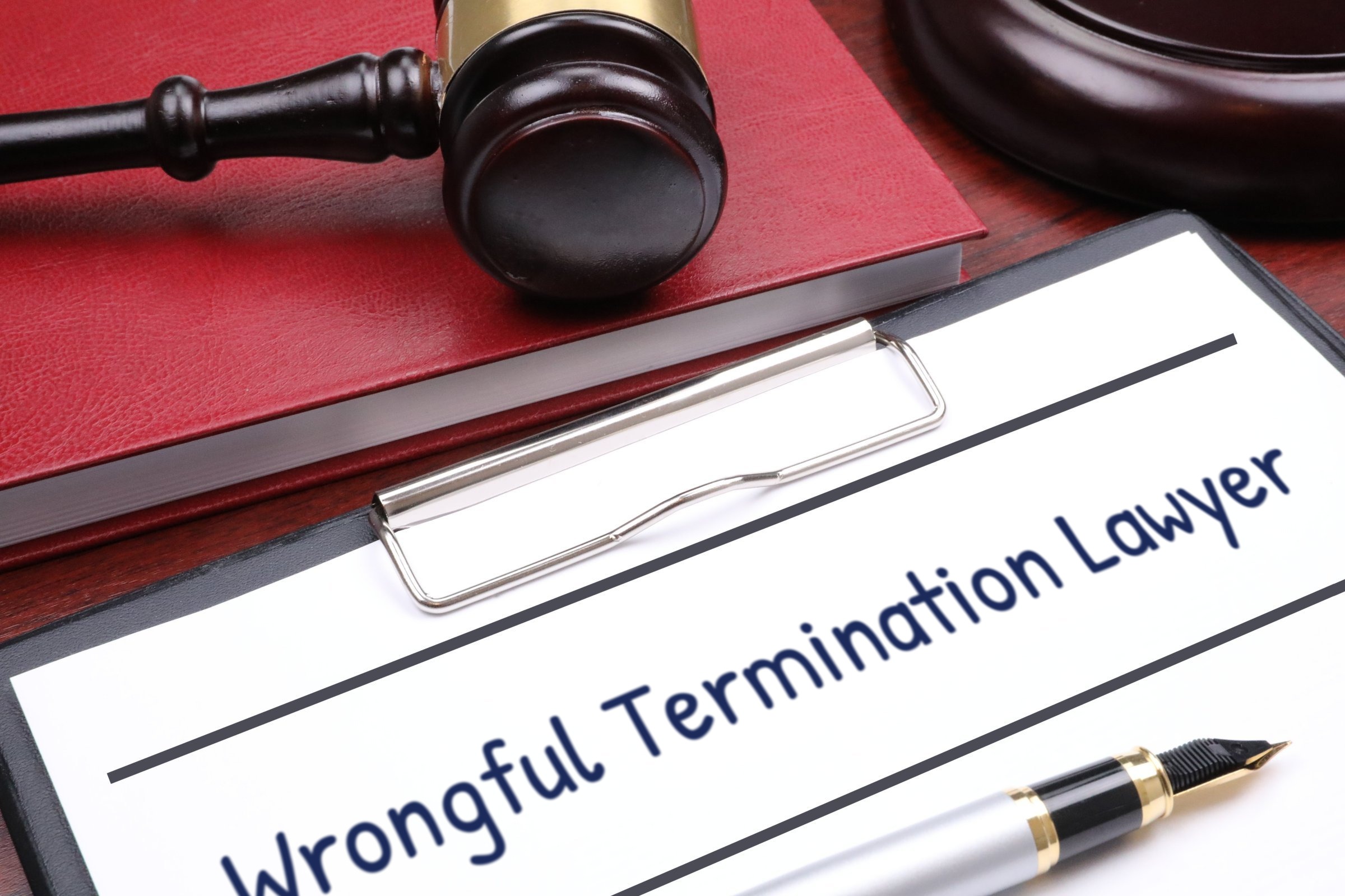 Clipboard with red book, gavel and fountain pen template with the words "Wrongful Termination Lawyer" printed on the surface