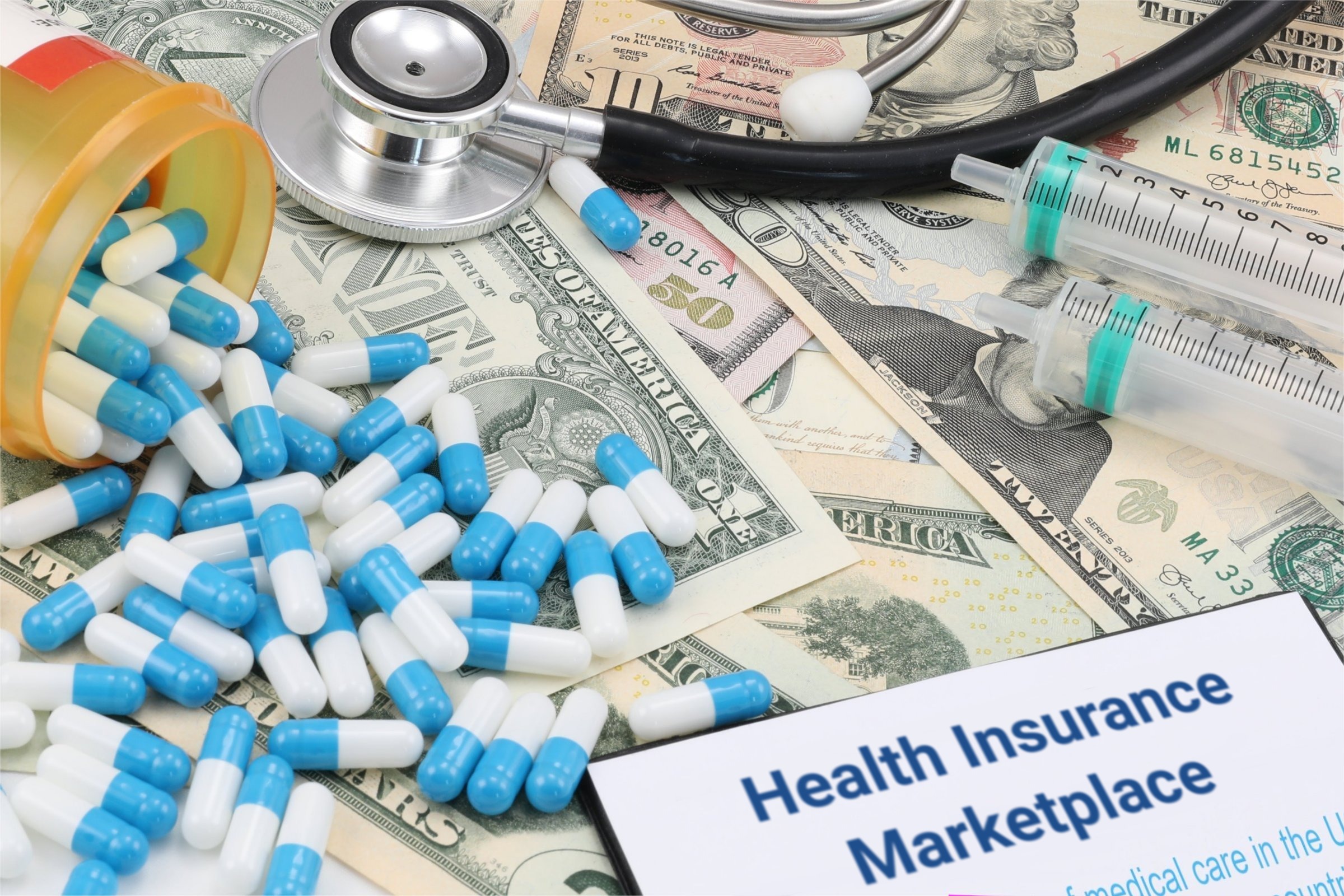 Capsules, syringes and dollar bills template with the words "Health Insurance Marketplace" printed on the surface