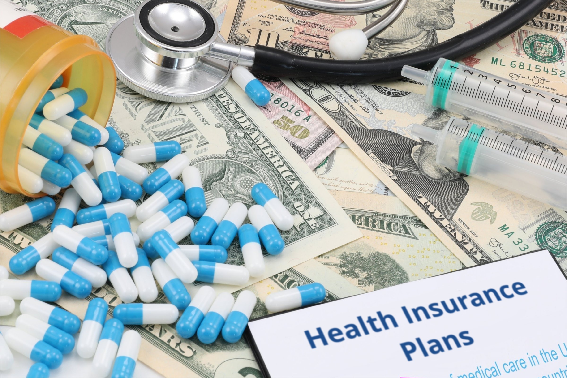 Capsules, syringes and dollar bills template with the words "Health Insurance Plans" printed on the surface