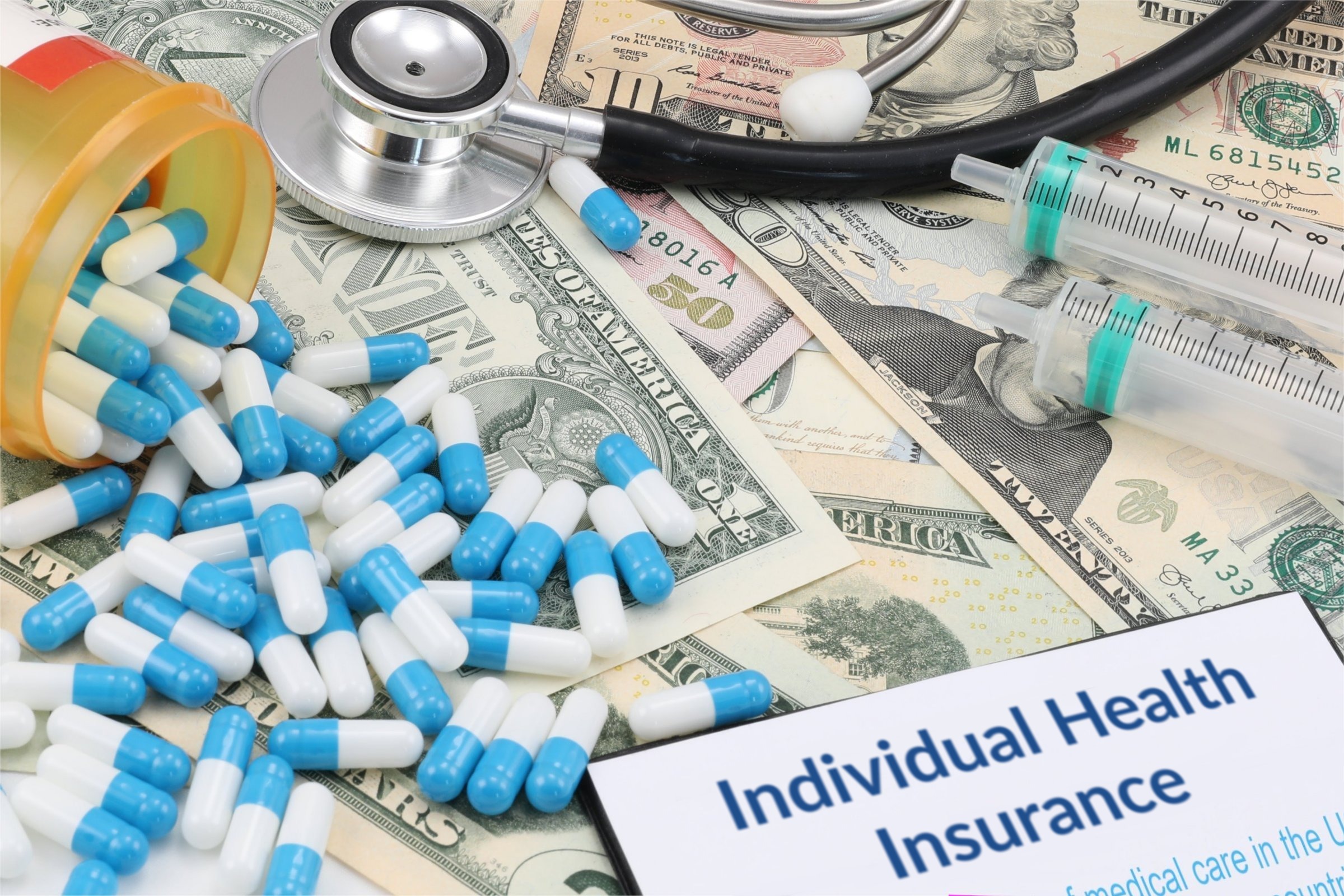 Capsules, syringes and dollar bills template with the words "Individual Health Insurance" printed on the surface
