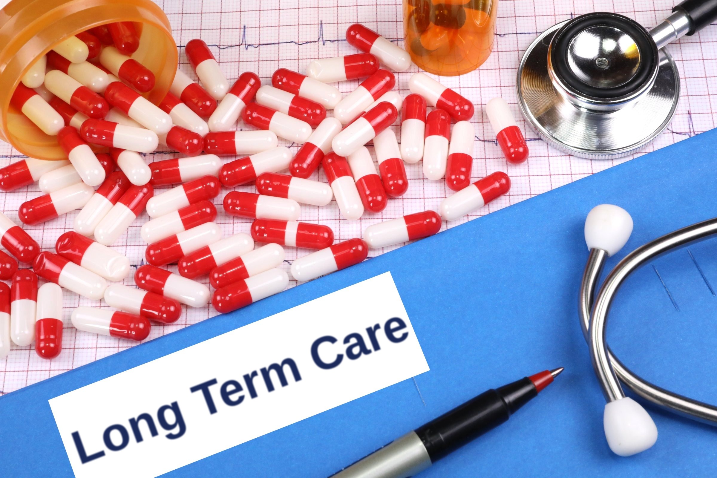 Red capsules on a blue folder with a blank label template with the words "Long Term Care" printed on the surface