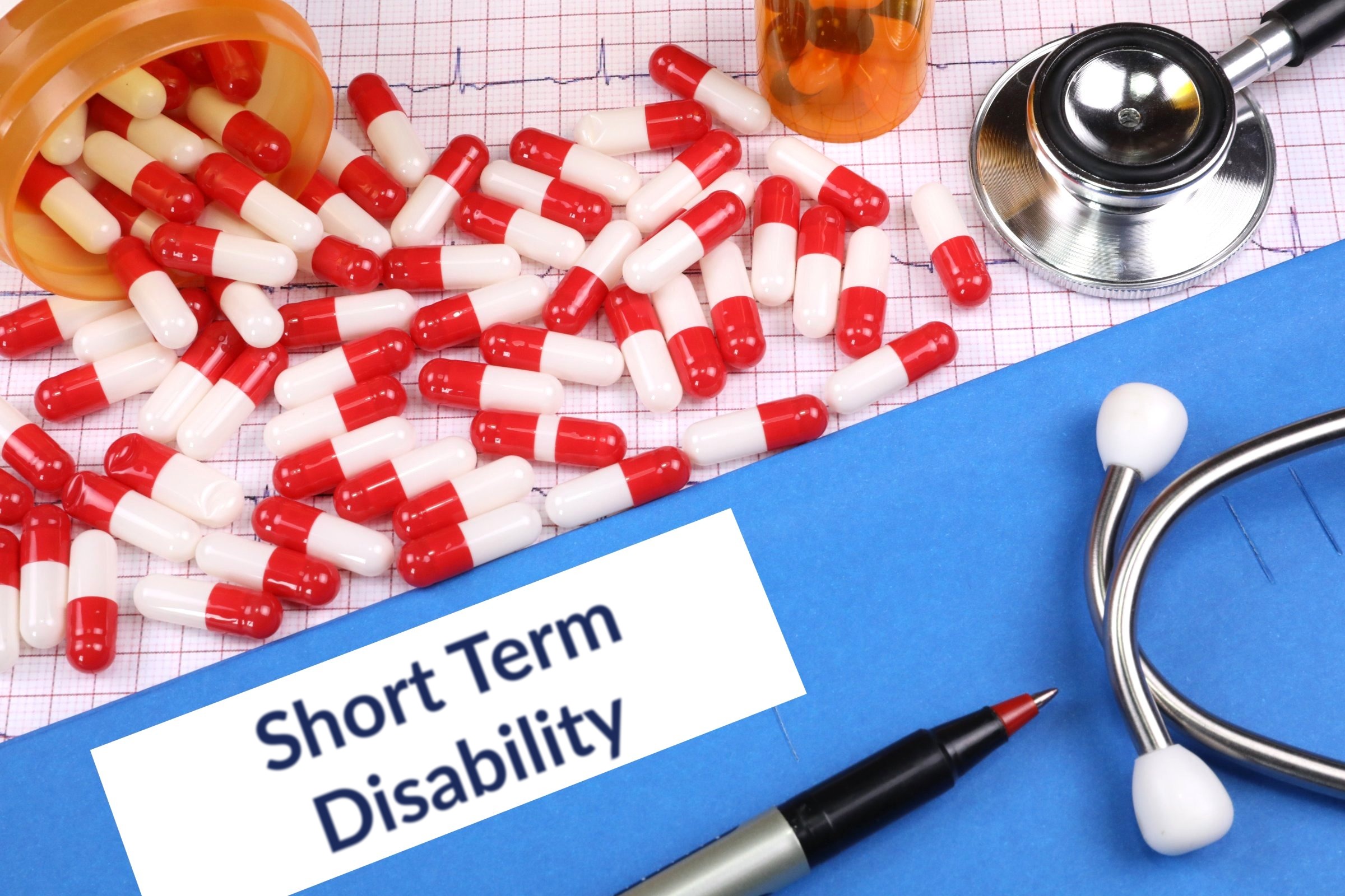 Red capsules on a blue folder with a blank label template with the words "Short Term Disability" printed on the surface