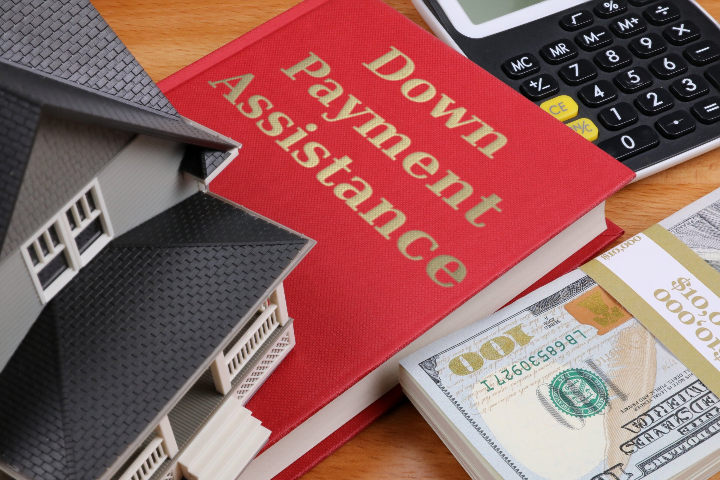 Red book with a model house and dollars template with the words "Down Payment Assistance" in metallic foil lettering